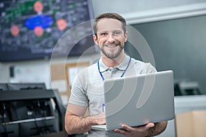 Handsome man standing with open laptop indoors