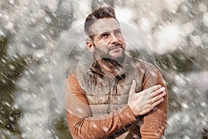 Handsome man standing outside while snowing fall