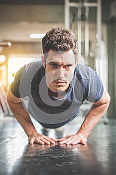 Handsome man and strong guy doing push ups exercise in fitness gym