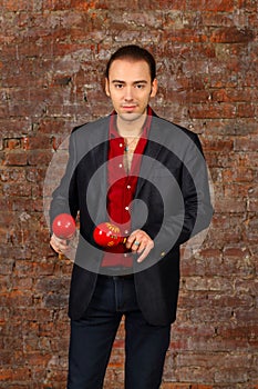 Handsome man in suit stands with red maracas in
