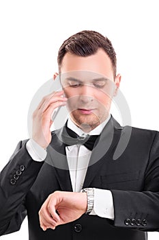 Handsome man in suit talking on the phone and looking at his wristwatch