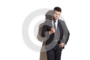 Handsome man in suit and tie standing against wall