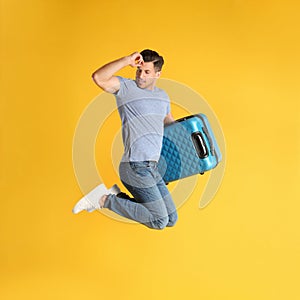 Handsome man with suitcase for summer trip jumping on background. Vacation travel