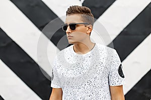Handsome man in sunglasses and a white T-shirt with spots