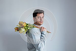 Handsome man with sunset safari flower on gray background