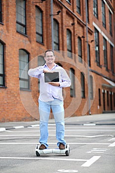 Handsome man with tablet rides GyroScooter near photo