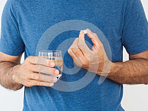 Handsome man taking pill on white background. Healthcare and med