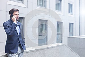 Handsome man is talking on telephone outdoors