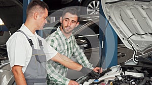 Handsome man talking to car mechanic at the repair station