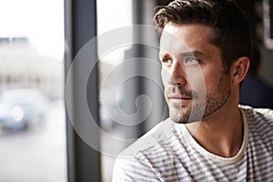 Handsome man, thinking and vision by window at cafe for ambition, travel or sightseeing. Face of male person waiting in