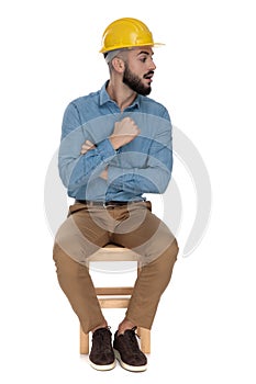 Handsome man threatening with fist while sitting with arms folded