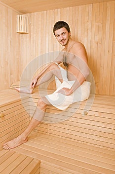 Handsome man in a towel relaxing in sauna