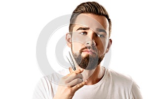 Handsome man trimming his beard with a scissors