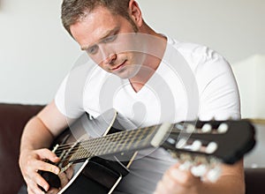 Handsome man tuning guitar.