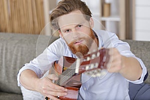 handsome man tuning guitar at home