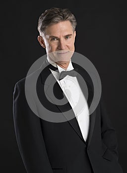 Handsome Man In Tuxedo Standing Against Black Background