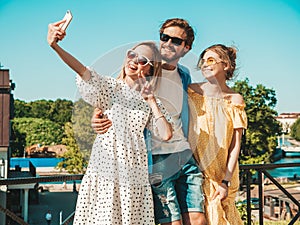 Handsome man and two beautiful women posing outdoors