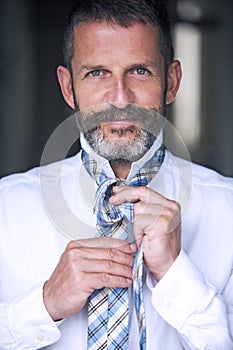 Handsome man tying his tie