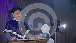 handsome man university lecturer solemnly congratulates graduates on the end of academic year using video camera