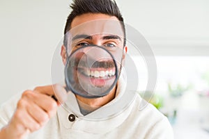 Handsome man using magnifying glass, doing funny faces