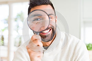 Handsome man using magnifying glass, doing funny faces