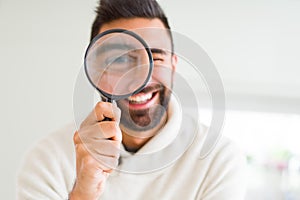 Handsome man using magnifying glass, doing funny faces