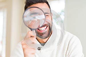 Handsome man using magnifying glass, doing funny faces