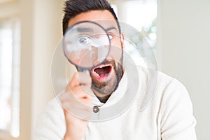 Handsome man using magnifying glass, doing funny faces