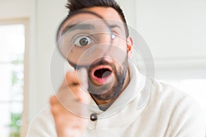 Handsome man using magnifying glass, doing funny faces