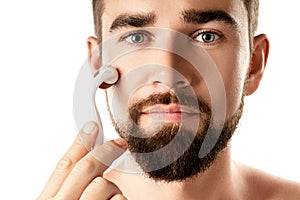 Handsome man using meso roller for better beard growth photo