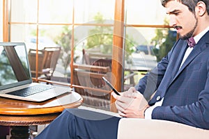 Handsome man using a mobile phone and laptop at cafe