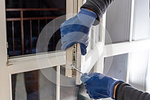 Handsome man using a screwdriver to install a window handle and looking at the camera. Making a house cozy and warm