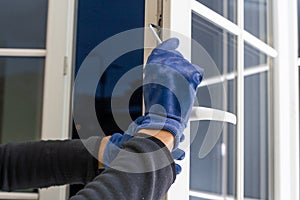 Handsome man using a screwdriver to install a window handle and looking at the camera. Making a house cozy and warm