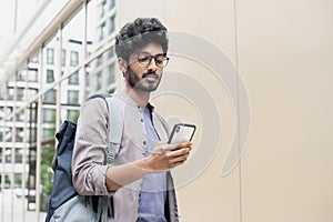Handsome man using smartphone in a city. Smiling student men texting on his mobile phone. Young businessman with mobile phone