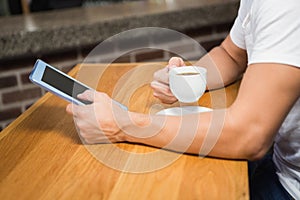 Handsome man using tablet and having coffee