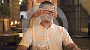 Handsome man waiting woman in restaurant and watching to clock at dinner table. Young woman closing eyes boyfriend with