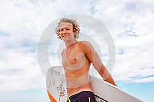 Handsome man walk with white blank surfing board wait for wave to surf spot at sea ocean shore. Concept of sport
