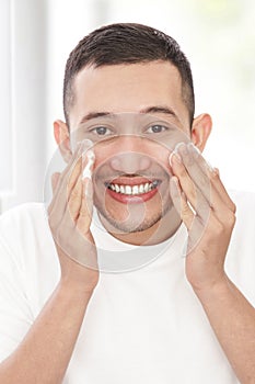 Handsome man washing his face using facial foam