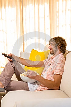 Handsome man watching TV and eating pop corn