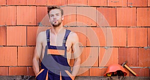 Handsome man wear overalls. Break for relax. Sexy laborer. Attractive worker. Construction. Worker brick wall background