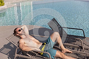 handsome man wear sunglasses lying relax time at poolside, lifestyle travel in holiday vacation. relaxation concept