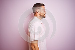 Handsome man wearing elegant summer shirt and sunglasses over pink isolated background looking to side, relax profile pose with