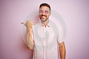 Handsome man wearing elegant summer shirt and sunglasses over pink isolated background smiling with happy face looking and