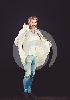 Handsome man wearing jeans pants and a coat posing at studio. Men's beauty, seasonal fashion. Studio shot.