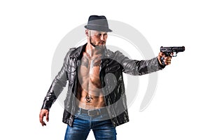 Handsome man wearing leather jacket on naked muscular torso pointing gun to camera, on dark smoky background, looking