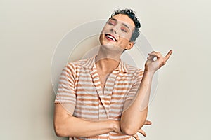 Handsome man wearing make up wearing casual t shirt with a big smile on face, pointing with hand and finger to the side looking at