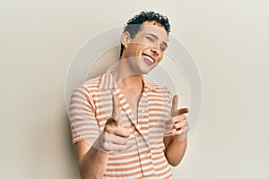 Handsome man wearing make up wearing casual t shirt pointing fingers to camera with happy and funny face