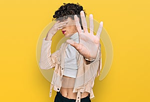 Handsome man wearing make up and woman clothes covering eyes with hands and doing stop gesture with sad and fear expression