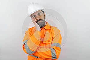 Handsome man wearing reflecting jacket and hardhat tired and posing with hand.