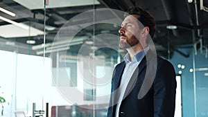 Handsome man wearing suit running hand over face and gazing away indoors